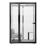 Black soundproof pod with glass door and interior chair and small side table